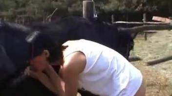 Tanned brunette with bangs sucking a horse's cock